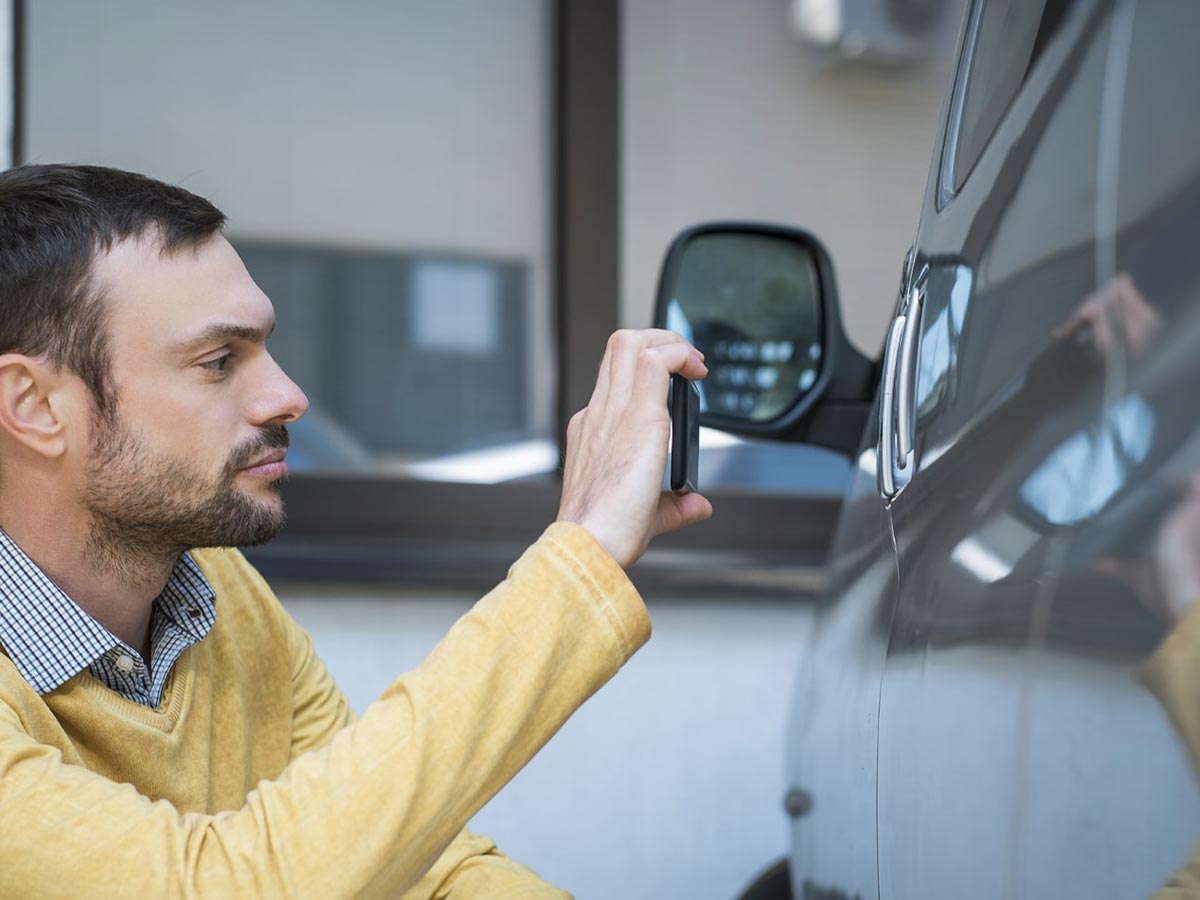 nationwide overspray handling insurance claims - insurance adjuster taking photos of the car overspray damage